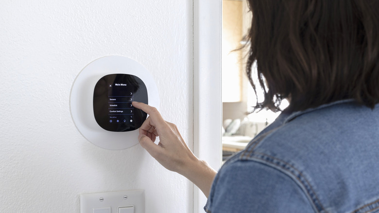 A person adjusting a smart thermostat