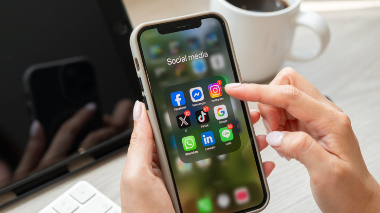 finger hovering over instagram icon in social media app on iphone display