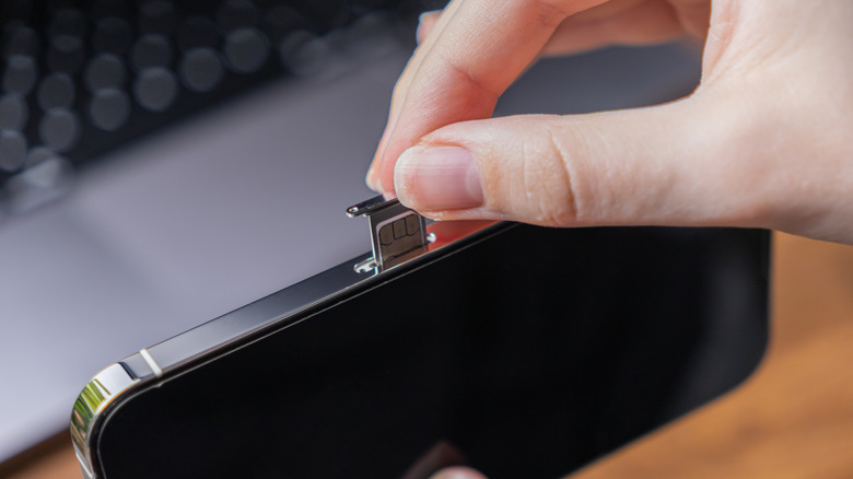 person taking sim card out of side of iphone