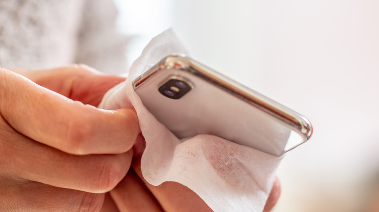 A person cleaning their phone screen with a wet tissue