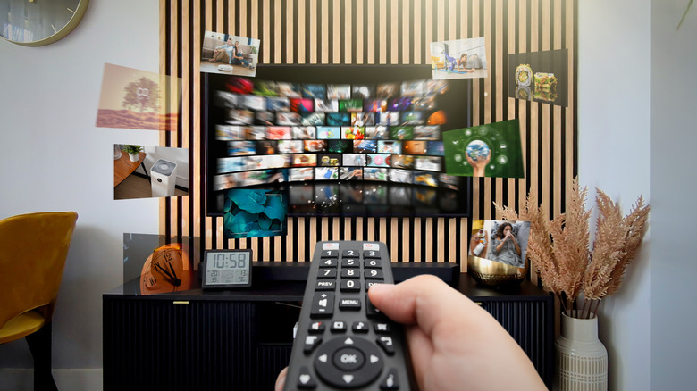 A person aiming a TV remote at a wall-mounted TV.