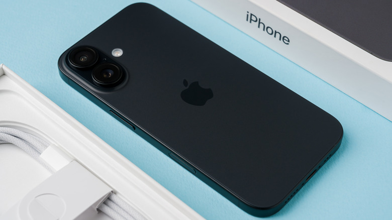 An Apple iphone on display next to its box and charging cable