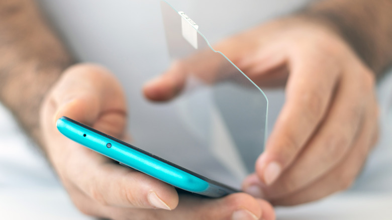 a person placing a screen protector on a phone that has a blue case