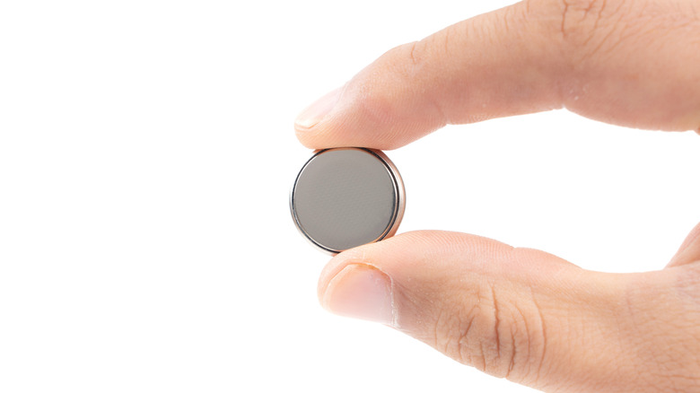 Close-up of hand holding tiny battery