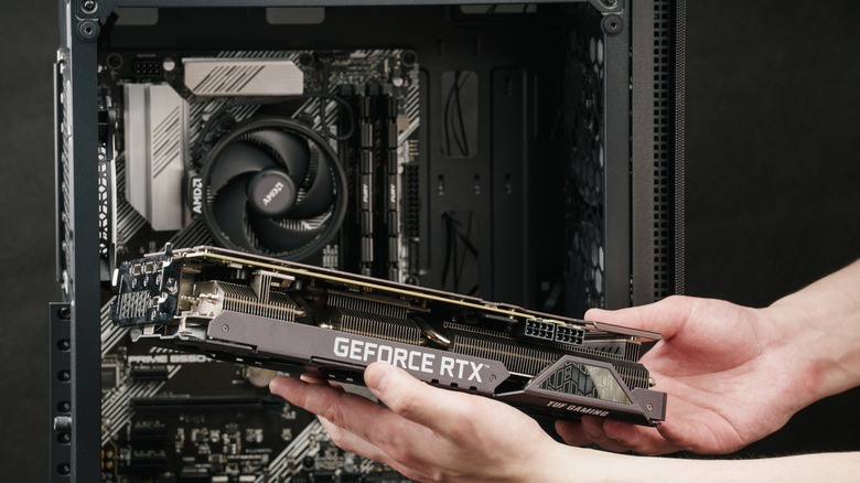 A person installing Nvidia GeForce RTX graphics card into a PC case.