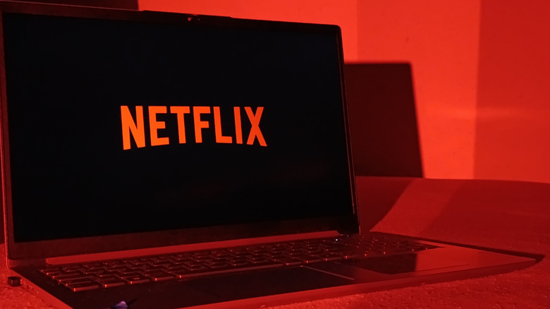 The Netflix logo on a laptop's screen in a red room.