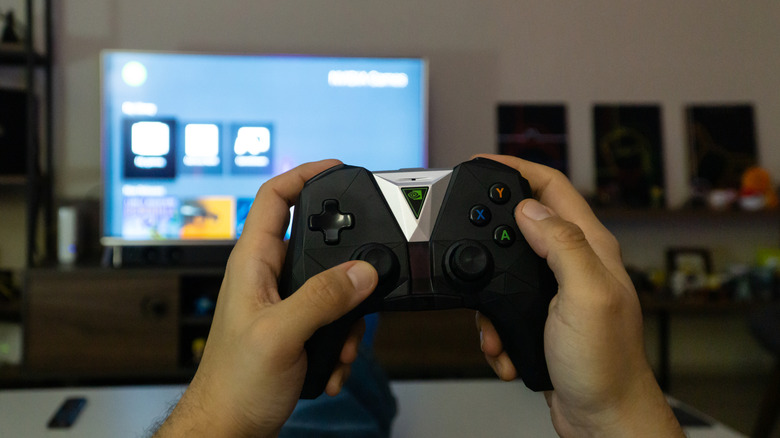 Person holding Nvidia Shield controller with TV in background
