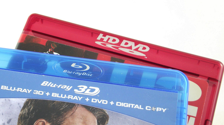 The top of a red HD DVD case under a blue Blu-ray case against a white background.