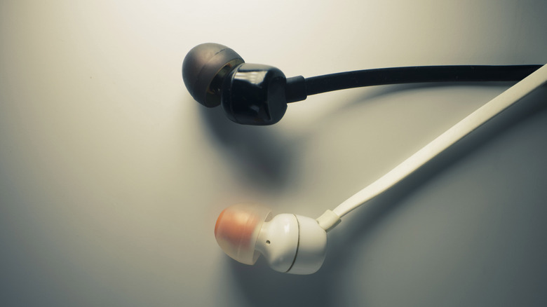 Wired earbuds set against an off-white backdrop.