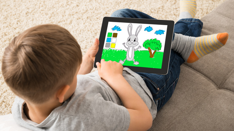 A child using a tablet at home on a couch