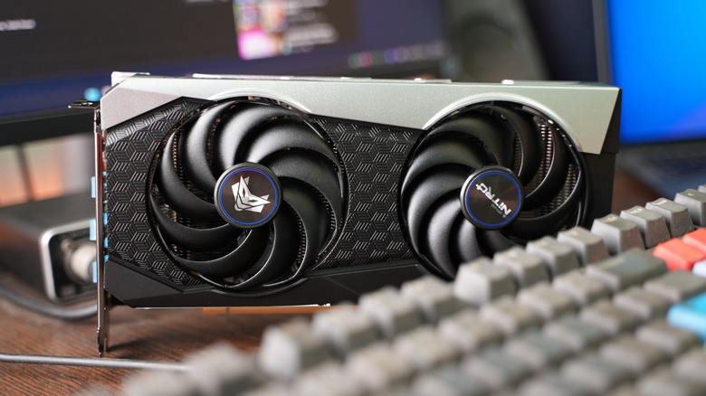 An AMD RX 6000-model graphics card sits on a desk behind a mechanical keyboard