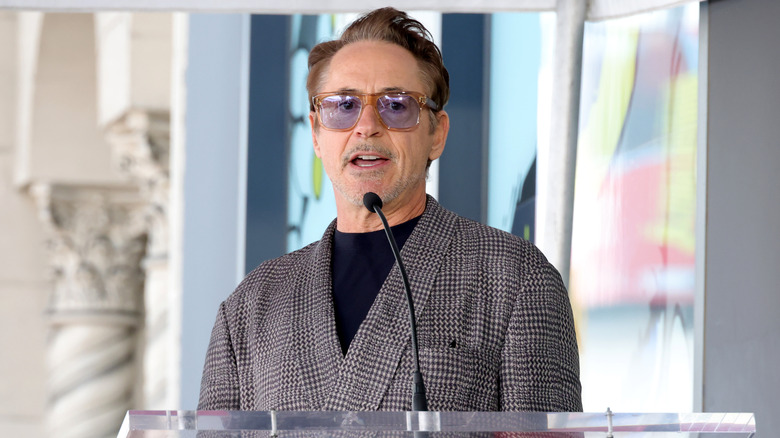 Robert Downey Jr. on a podium in sunglasses and a suit
