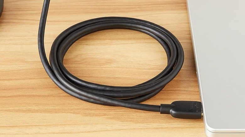 A promotional image for the Amazon Basics HDMI 2.0 cable, the image shows the cord furled as its plugged into a laptop