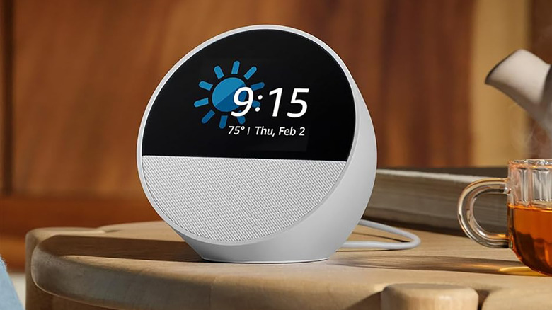 A white Amazon Echo Spot on a table showing the weather, date, and time