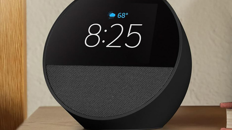 A black Amazon Echo Spot on a table showing the weather and time