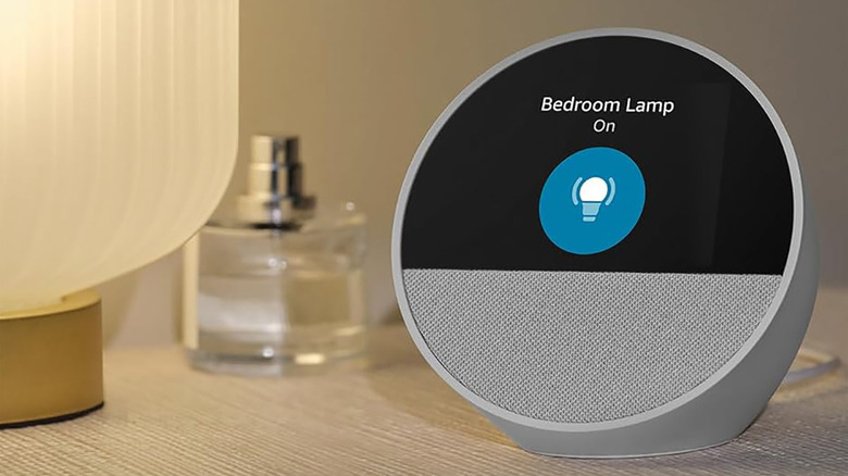 A white Amazon Echo Spot on a nightstand showing that bedroom lamp is on