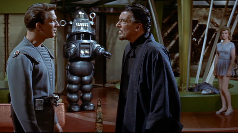 Dr. Morbious and Commander Adams have an altercation, while Robby the robot and Altaira look on worringly.