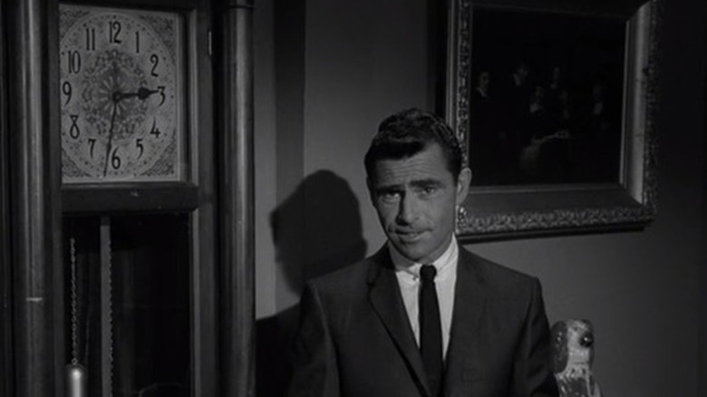 Rod Serling standing in a next to a clock on "The Twilight Zone."