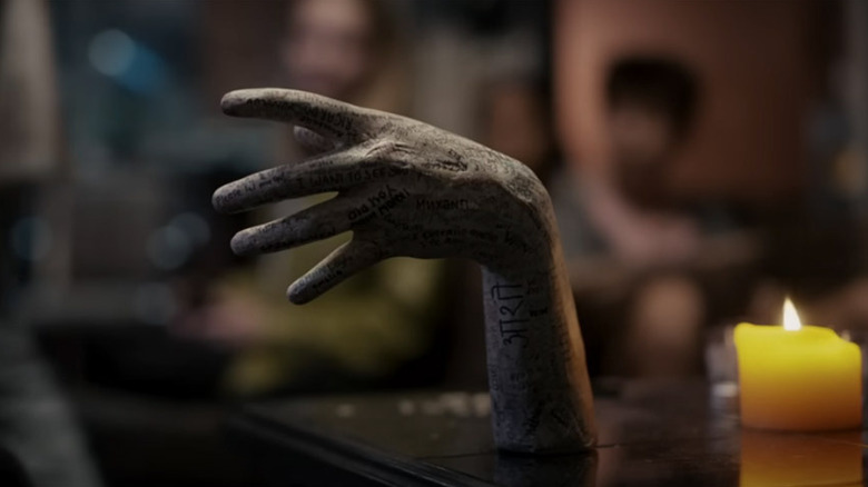 The terrifying severed embalmed hand next to a candle in 