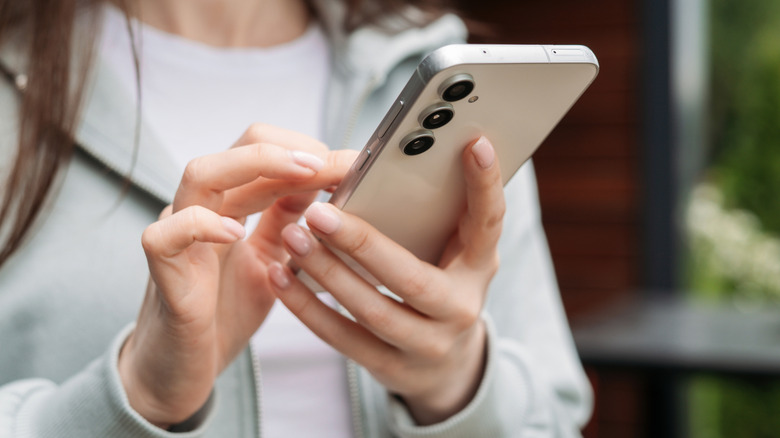 A woman holding the Samsung Galaxy S25 smartphone.