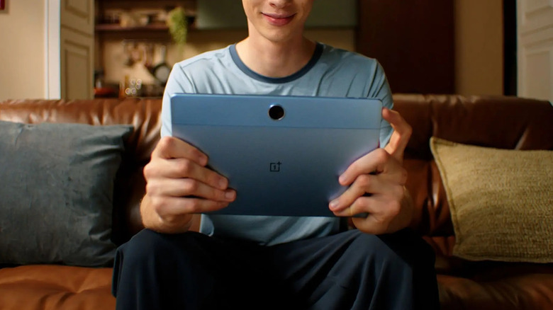 A person holding a OnePlus Pad Lite while sitting on a couch