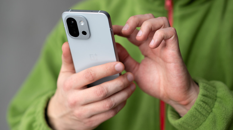 Close-up of a person holding a OnePlus 13T smartphone