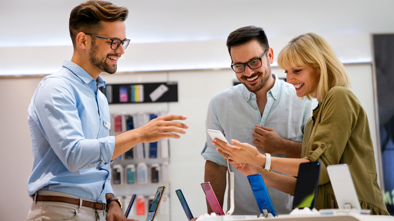 A couple being helped by a salesperson in an electronics store.