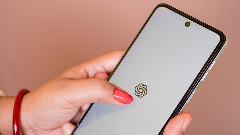 A person using a smartphone with the OpenAI logo seen on the display.