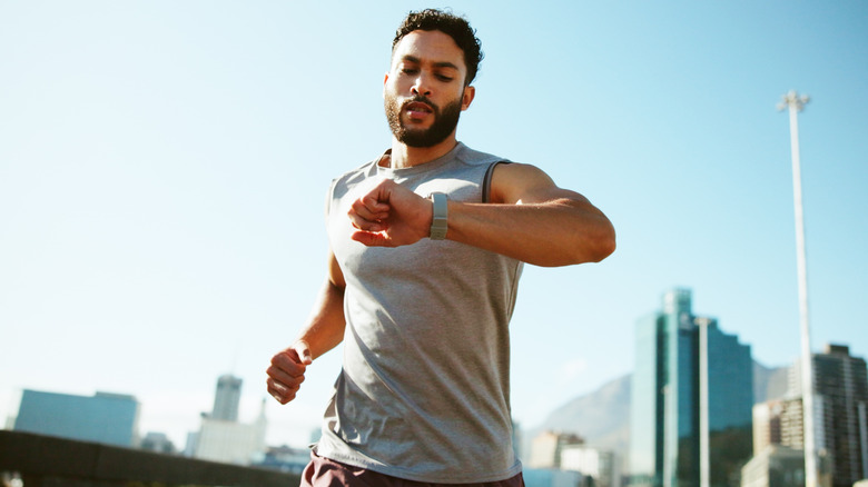 A man checks his smartwatch while running