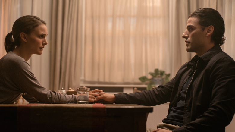 Lena and Kane holding hands while sitting at a table in their home