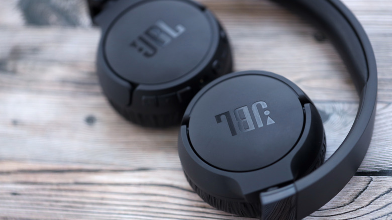 A pair of JBL headphones placed on a wooden surface.
