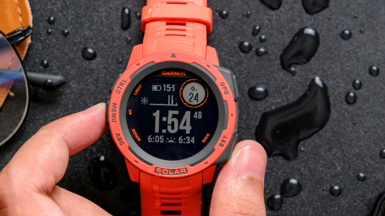An orange Garmin smartwatch showing the time.