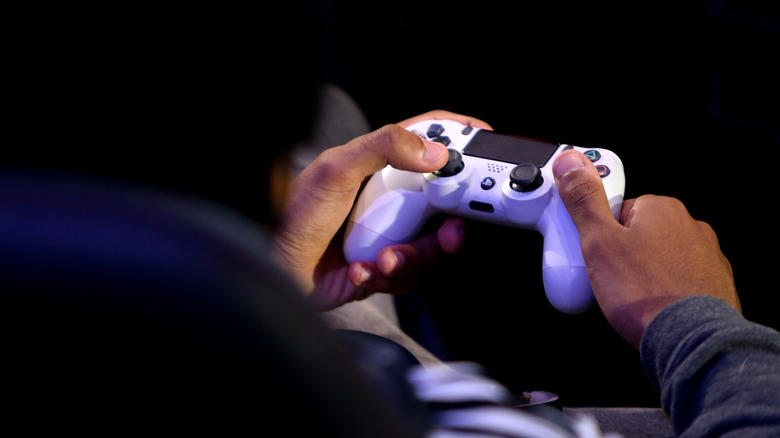 Person holding white DualShock 4 PlayStation 4 controller