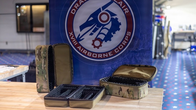 Three Modular Drone Cases sit open on a table in front of the Dragon's Lair banner.