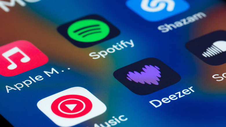 Smartphone displaying logos for Spotify, Apple Music, Shazam, Deezer, and YouTube Music