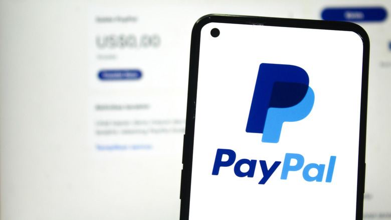 PayPal logo on a phone in front of the PayPal website