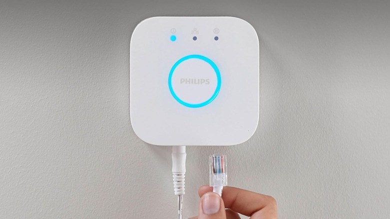 A person connecting an Ethernet cable to a Hue Bridge.