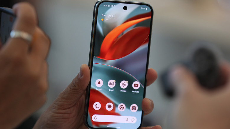 The Pixel 9 in hand with the display turned on.