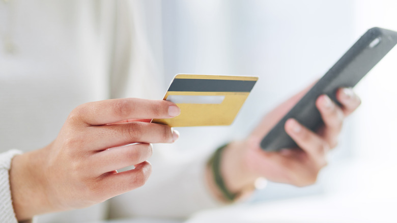Person holding credit card and phone