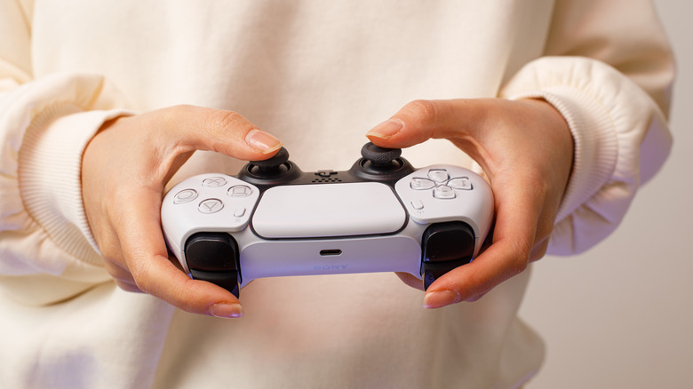 Person holding PlayStation 5 DualSense controller
