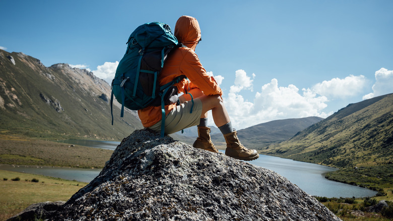 a person out backpacking, sitting and enjoying a mountain lake view