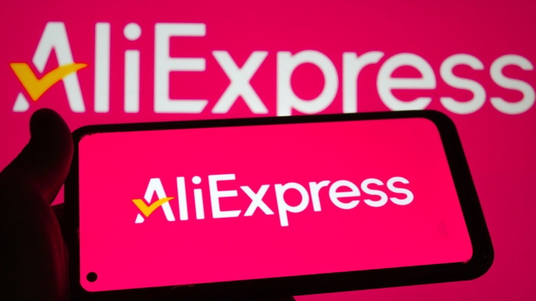 A phone with the AliExpress logo on it in front of a screen with a larger AliExpress logo