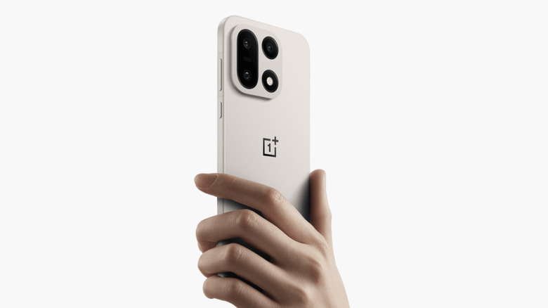 A person holding the OnePlus 15 in Sand Storm Color
