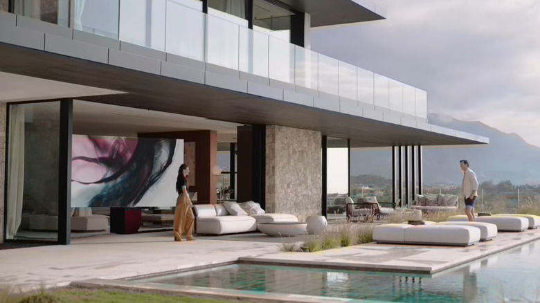 a man and woman on a pool terrace with a TV.