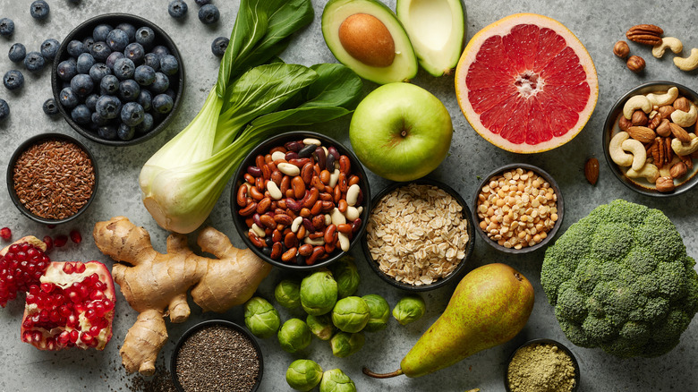 vegetables, nuts, and fruits on a tabletop side by side