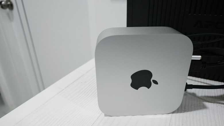 Apple Mac Mini placed on a white work desk in behind a monitor