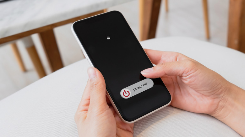 A woman holding a phone in her hands, about to swipe the power button to power it off