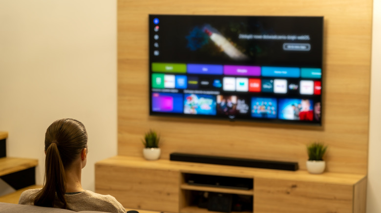Smart TV on in the living room with woman watching from the couch.