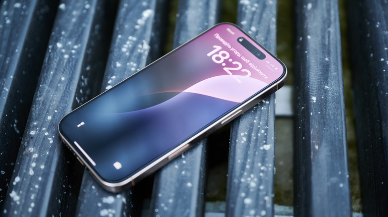 A locked iPhone on a bench, with the Face ID authentication animation showing in the Dynamic Island.