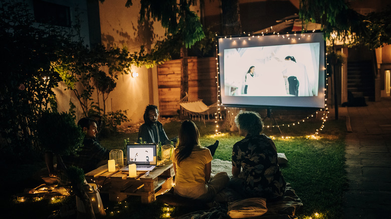 A group of people watch a show on an outdoor projector